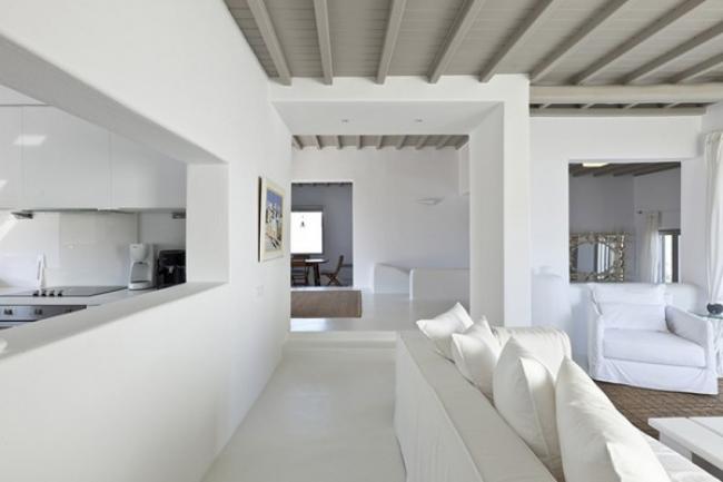 греческие интерьеры-белая гостиная с серым балочным потолком и проемом нм кухню