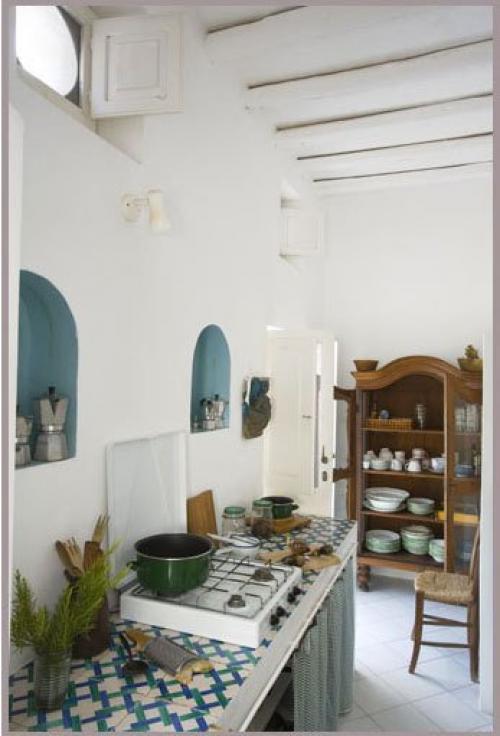 кухня в средиземноморском стиле с белыми оштукатуренными стенами и стлом обложенным плиткой