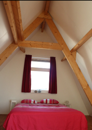 спальня в мансарде с открытыми деревянными балками
