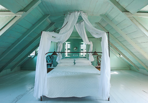 кровать с балдахином в интерьере спальни в мансарде