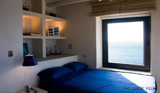греческие интерьеры - спальня полками в изголовье кровати и синим покрывалом